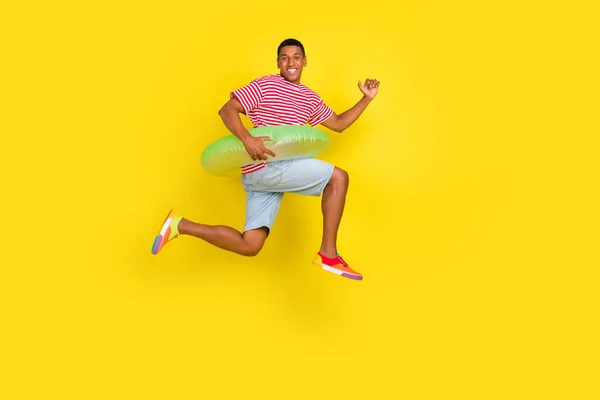 Foto lateral de perfil de longitud completa de chico salto celebrar anillo nadador correr usar pantalones cortos de la camisa aislados sobre fondo de color amarillo — Foto de Stock