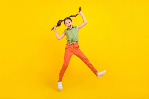 Foto de encantadora menina pré-adolescente animado vestido top verde saltando alto sorrindo isolado cor amarela fundo — Fotografia de Stock