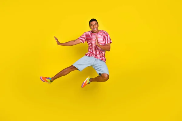 Full size foto di ragazzo salto kick box spazio vuoto usura rosso a righe t-shirt pantaloncini isolati su sfondo di colore giallo — Foto Stock
