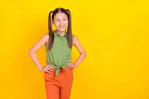 Photo of sweet little tails hairdo girl wygląd pomo nosić zielony top pomarańczowe spodnie izolowane na żółtym tle — Zdjęcie stockowe