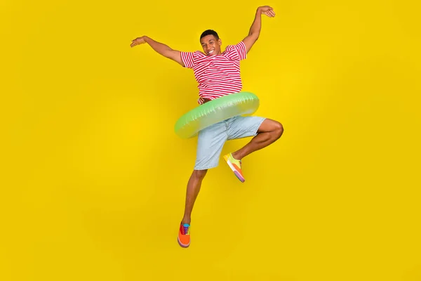 Full size photo of guy jump like ballerina hold ring swimmer wear shorts shirt isolated over yellow color background