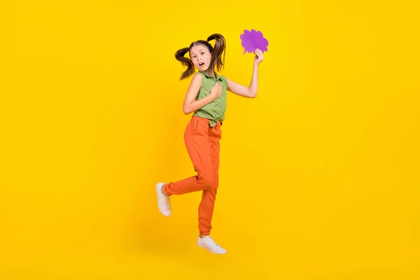 Foto de doce impressionado menina pré-adolescente vestido top verde saltando alta segurando falando nuvem espaço vazio isolado cor amarela fundo — Fotografia de Stock