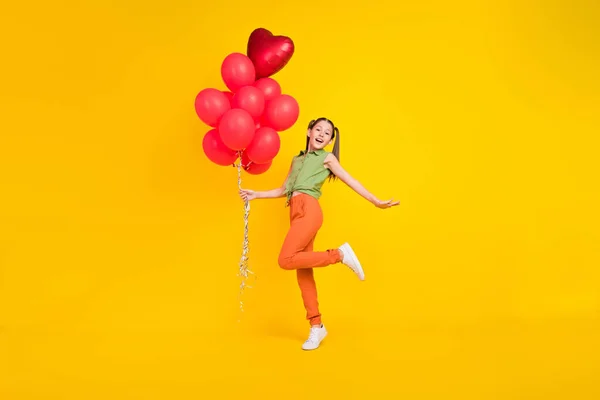 Foto de estudante despreocupado engraçado menina desgaste verde camisa sorrindo segurando vermelho bolhas buquê isolado cor amarela fundo — Fotografia de Stock