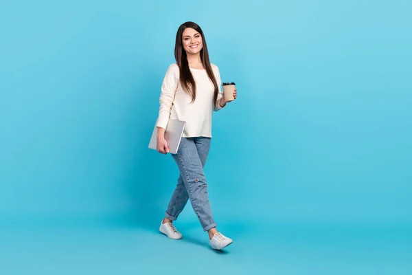 Foto lateral de perfil de cuerpo completo de la joven chica alegre caminar beber latte caliente celebrar reunión portátil aislado sobre fondo de color azul —  Fotos de Stock