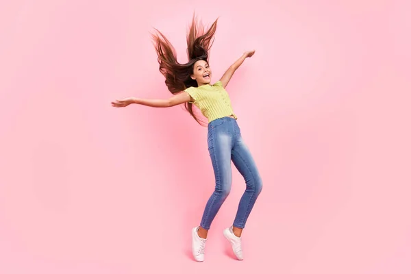 재미있는 작은 숙녀 댄스 스탠드 발가락던지기 머리를 하고 있는 사진 녹색 상단 청바지 스니커즈를 하고 있는 핑크 색 배경 — 스톡 사진