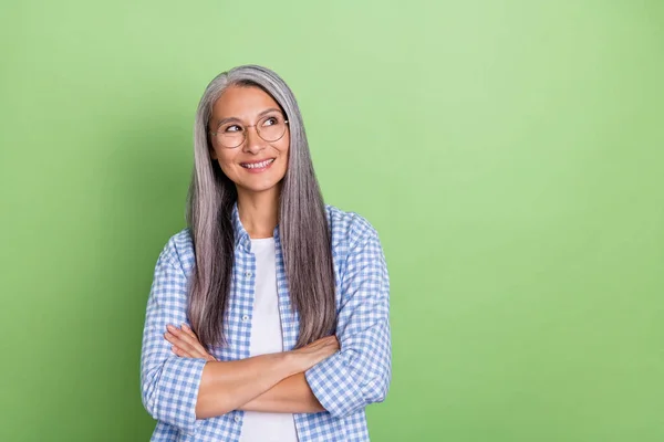 Foto van grappige vlier wit kapsel dame gekruiste palmen kijken lege ruimte dragen bril blauw shirt geïsoleerd op groene kleur achtergrond — Stockfoto