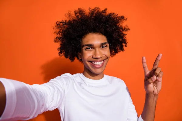 Bild av glad positiv kille bära vit skjorta halv inspelning själv video v-tecken isolerad orange färg bakgrund — Stockfoto