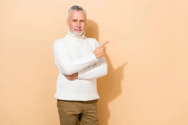 Retrato de atractivo contenido hombre de pelo gris demostrando copia vacía espacio en blanco anuncio aislado sobre fondo de color pastel beige — Foto de Stock