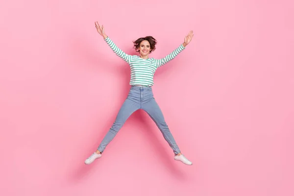 全身写真の感動的なミレニアルボブヘア女性ジャンプはピンクの背景に隔離されたシャツジーンズの靴を着用 — ストック写真