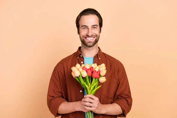 照片上自信迷人的男友准备约会时，捧着一束鲜花穿着休闲装孤零零的米色背景 — 图库照片