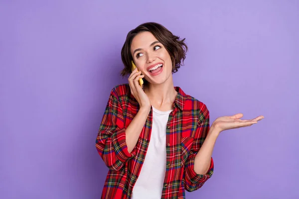 Foto van zoete jonge brunette dame praten telefoon slijtage geruite shirt geïsoleerd op paarse kleur achtergrond — Stockfoto