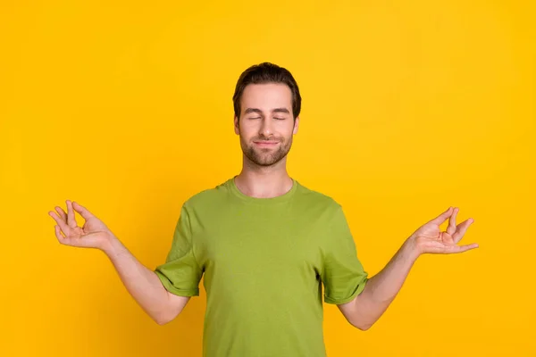 Фото сонного брюнетки зачіски тисячоліття хлопець тримає пальці в зеленій футболці ізольовані на яскраво-жовтому кольоровому фоні — стокове фото