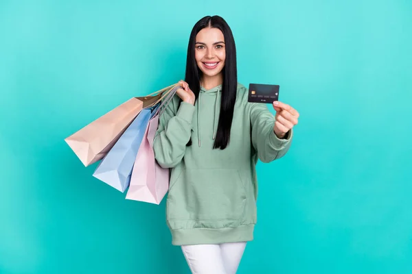 Photo of sweet millennial brunette lady do shopping hold card wear green sweatshirt isolated on teal color background — Stock Photo, Image