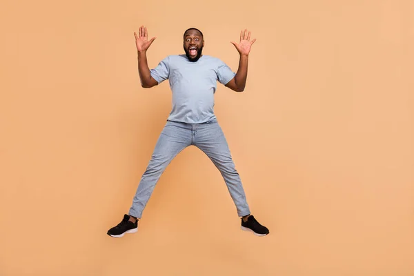 Plná délka tělo velikost pohled na atraktivní veselý chlap skákání s zábavou blázinec izolované přes béžové pastelové barvy pozadí — Stock fotografie