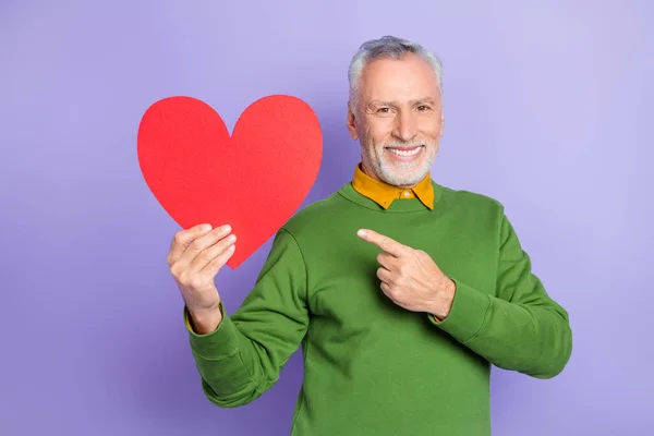 Foto di dolce carino uomo pensionato vestito pullover verde che indica grande cuore isolato colore viola sfondo — Foto Stock