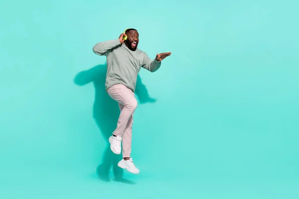 Full längd kroppsstorlek bild av attraktiv glad aktiv kille hoppa lyssna hit pop isolerad över ljusa teal turkos färg bakgrund — Stockfoto