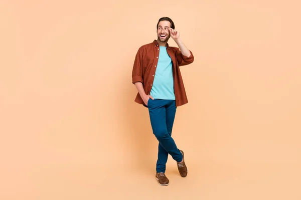 Zdjęcie podekscytowany ciekawy zabawny człowiek wygląda puste miejsce nosić specyfikacje casual strój odizolowany beżowy kolor tła — Zdjęcie stockowe