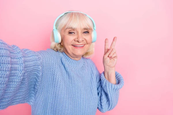 Autoportrét atraktivní veselý šedovlasá žena poslech píseň mp3 ukazující V-znamení izolované přes růžové pastelové barvy pozadí — Stock fotografie