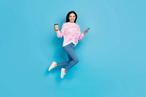 Pełna długość zdjęcie młodej dziewczyny skoczek energetyczne espresso używać mobilne szybkie połączenie 4g izolowane na niebieskim tle koloru — Zdjęcie stockowe