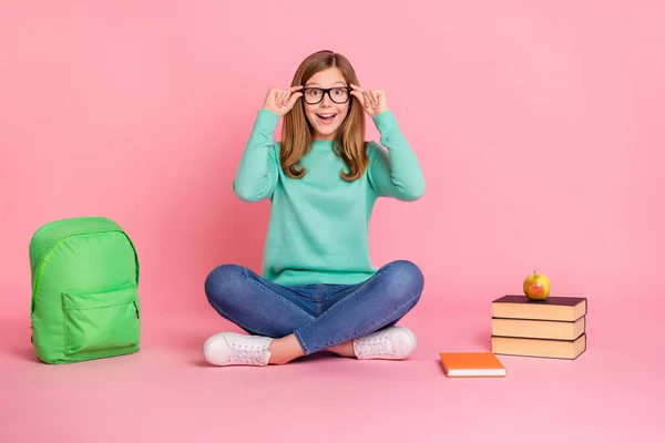 Şok olmuş bir kızın turkuaz süveter giydiği fotoğraf gözlük takıyor okul malzemeleri izole edilmiş pembe arka plan. — Stok fotoğraf