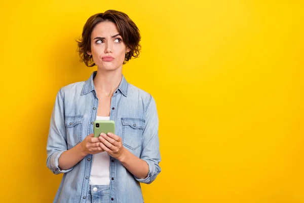Φωτογραφία της νεαρής γυναίκας φαίνονται κενό χώρο αβέβαιη χρήση κινητό τηλέφωνο app 4g απομονώνονται σε κίτρινο χρώμα φόντο — Φωτογραφία Αρχείου