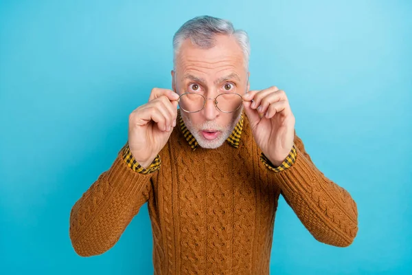 Фото впечатленного смешного пенсионера одетый коричневый пуловер руки очки большие глаза изолированы синий цвет фона — стоковое фото