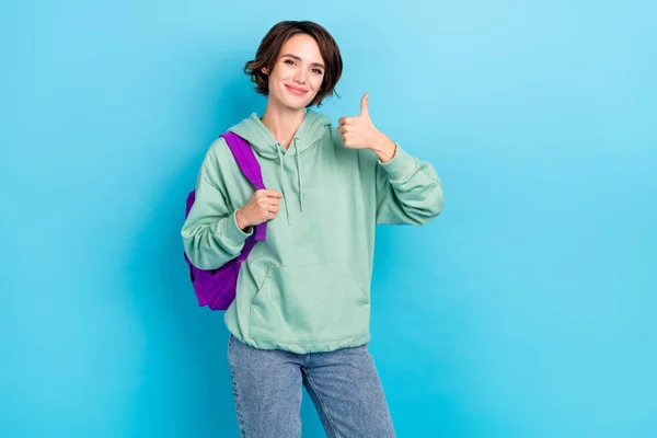 Foto de encantadora mulher doce usar mochila camisola verde mostrando polegar até fundo de cor azul isolado — Fotografia de Stock