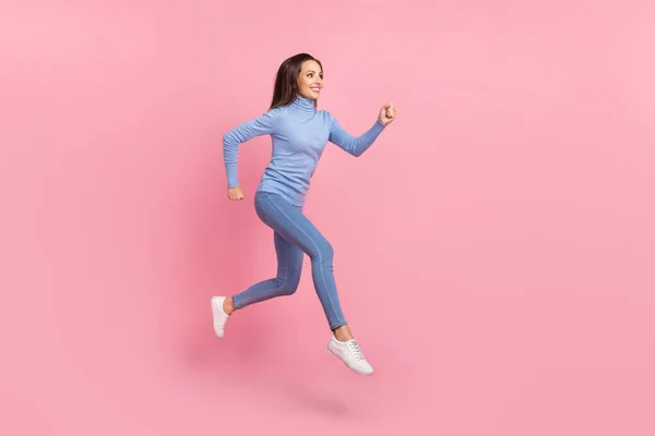 Foto de perfil de alegre salto de señora activa correr espacio vacío desgaste azul cuello alto jeans zapatillas aisladas de color rosa fondo —  Fotos de Stock