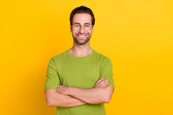 Zdjęcie chłodnej brody młody facet skrzyżowane dłonie nosić okulary zielony t-shirt izolowany na żółtym tle kolor — Zdjęcie stockowe
