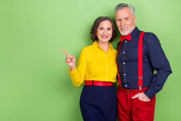 Retrato de dos personas positivas de edad indican dedo vacío espacio proposición noticias aisladas sobre fondo de color verde — Foto de Stock