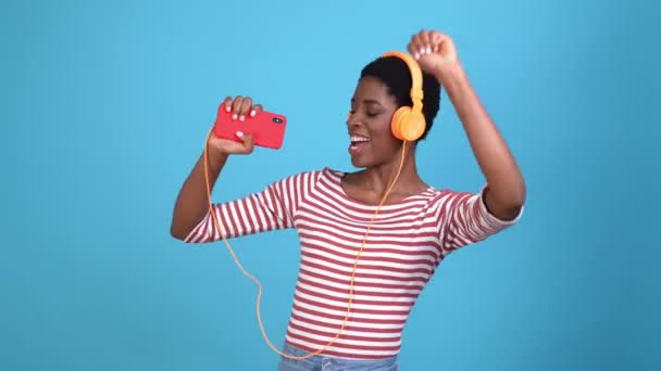 Lesben singen Kopfhörer Song Gerät isoliert blaue Farbe Hintergrund — Stockvideo