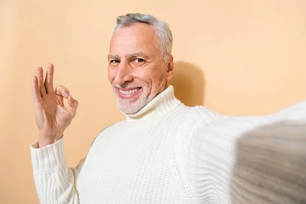 Self-portrait of attractive cheerful glad grey-haired man showing ok-sign ad isolated over beige pastel color background — Stock Photo, Image