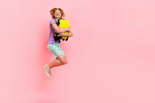Pleine longueur taille du corps vue d'attrayant gai gars sautant étreinte sac low cost compagnie aérienne isolé sur fond rose couleur pastel — Photo