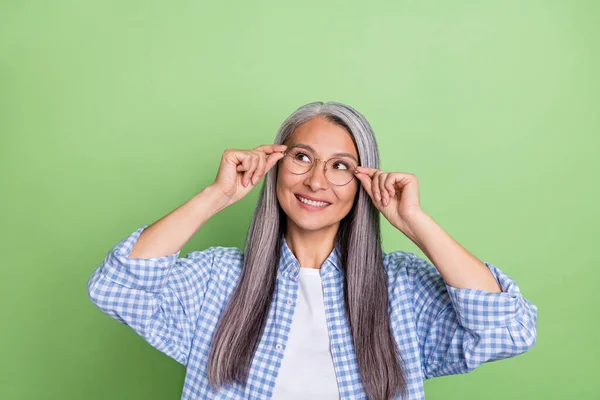 Fénykép aranyos öreg fehér frizura hölgy néz üres tér kopás szemüveget kék ing elszigetelt zöld színű háttér — Stock Fotó