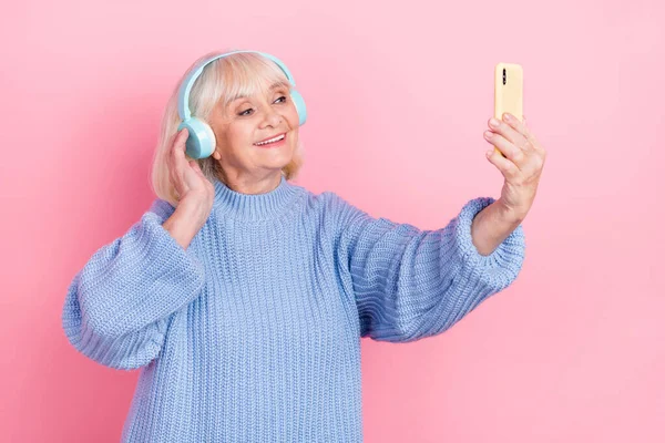 Porträt einer attraktiven, fröhlichen grauhaarigen Frau, die ein Selfie mit einem Pophit macht, isoliert über einem Hintergrund in rosa Pastellfarben — Stockfoto