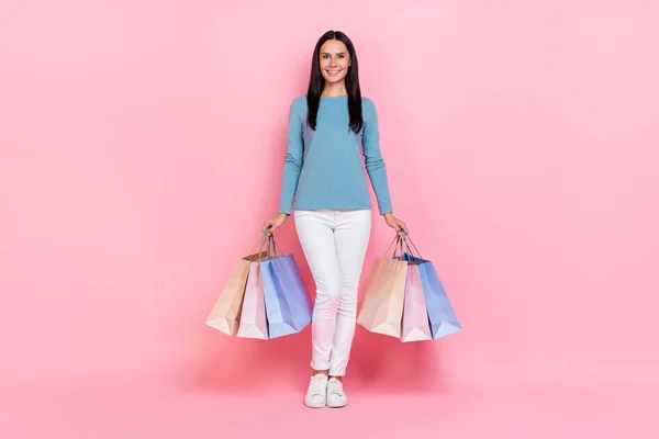 Fénykép fényes csinos nő visel kék ing gazdaság vásárlók séta elszigetelt rózsaszín szín háttér — Stock Fotó