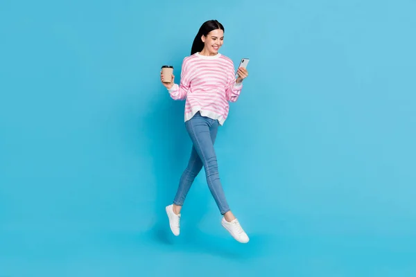 Фотографія повного тіла молодої дівчини виглядає мобільною, як пост-спільний напій латте кофеїн розрив ізольовано на синьому кольоровому фоні — стокове фото