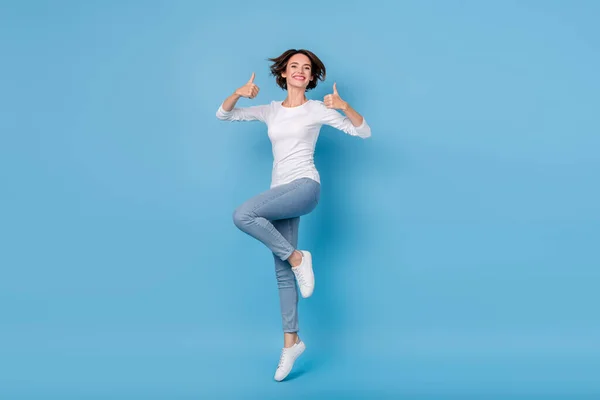 Full size foto van aantrekkelijke student leeftijd meisje springen tonen duimen-up promotie geïsoleerd op blauwe kleur achtergrond — Stockfoto