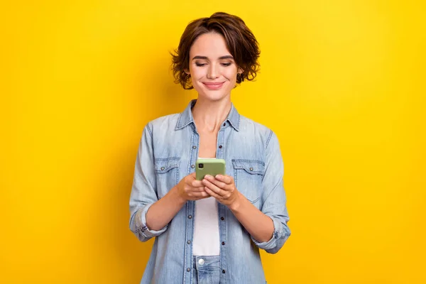 Photo of young lovely girl chat type sms comment download app use cellphone isolated over yellow color background