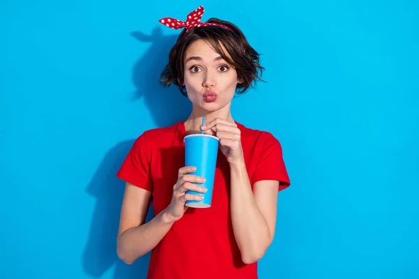 Fénykép a kacér millenniumi barna hölgy ital kopás piros póló fejpánt elszigetelt kék színű háttér — Stock Fotó