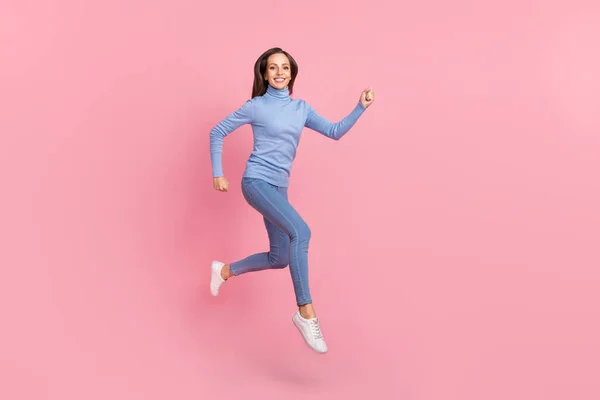 Foto de deportivo enérgico señora salto correr rápido prisa desgaste azul cuello alto jeans zapatos aislados de color rosa de fondo — Foto de Stock