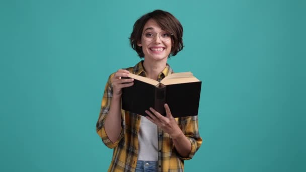 Wanita kutu buku membaca buku teks menarik latar belakang warna sian yang terisolasi — Stok Video