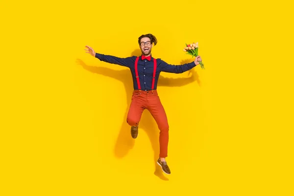 Lunghezza completa foto di giovane uomo energico ponticello fretta tenere fiori marito romanticismo isolato su sfondo di colore giallo — Foto Stock
