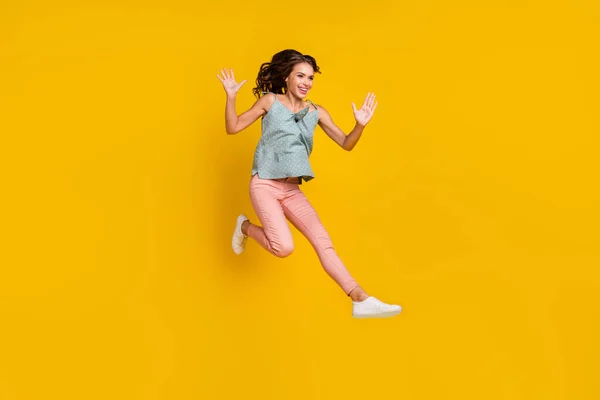 Full body foto van energieke positieve vrouw spring omhoog verhogen handen genieten van lege ruimte geïsoleerd op gele kleur achtergrond — Stockfoto