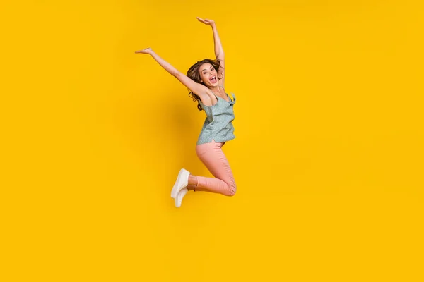 Teljes méretű fotó vidám pozitív fiatal nő ugrik fel emelje fel a kezét mosoly aktív elszigetelt sárga színű háttér — Stock Fotó