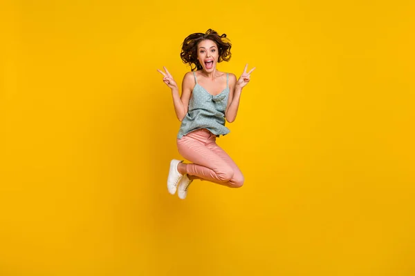 Heyecanlı mutlu kadının tam boy fotoğrafı yukarı zıplıyor V-işaretleri serin gülümsemesi sarı arka planda izole edilmiş. — Stok fotoğraf