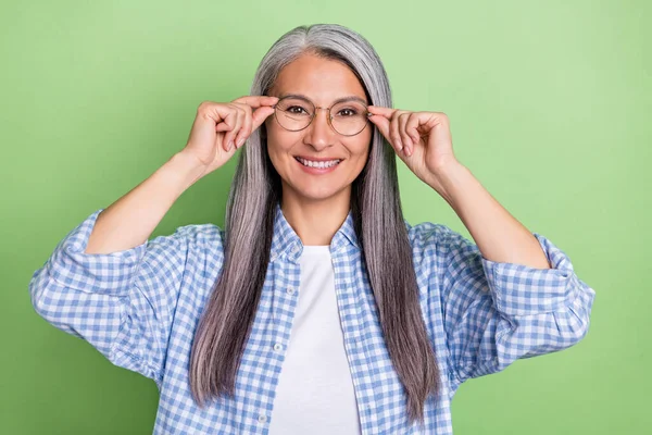 Foto de divertido anciano gris peinado señora look cámara desgaste gafas camisa azul aislado sobre fondo de color verde —  Fotos de Stock