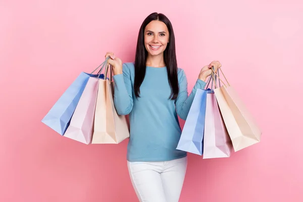 甜美漂亮的女士穿着蓝色衬衫笑着抱着购物者走在孤立的粉色背景上的照片 — 图库照片