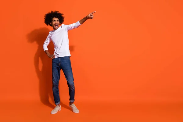 Foto av bedårande söt kille klädd vit skjorta ler pekar finger tomt utrymme isolerad orange färg bakgrund — Stockfoto