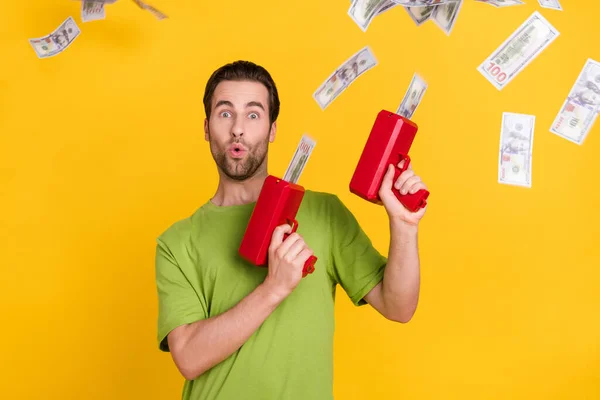 Foto de barba legal millennial cara segurar dinheiro arma desgaste verde t-shirt isolado no fundo de cor amarela — Fotografia de Stock
